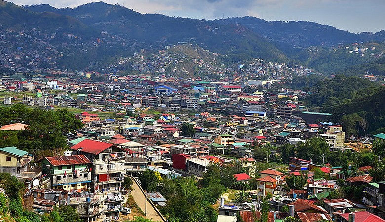 Expanse of buildings on flat, and steadily encroaching on mountainside areas